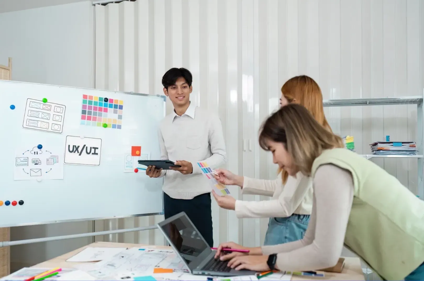 Person reviewing a wireframe flowchart and color swatches on a whiteboard for a Tucson web design project.