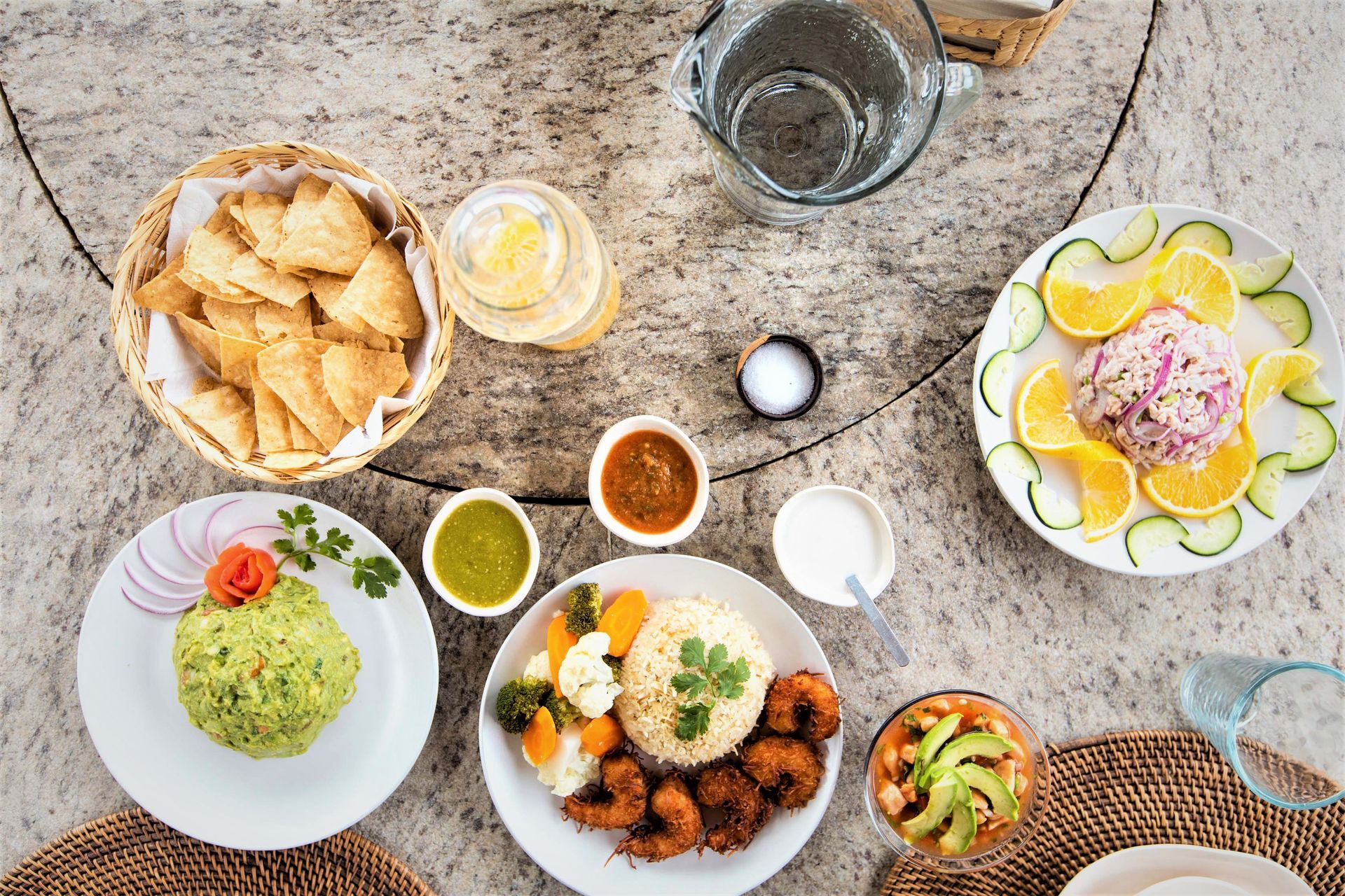 Vista aérea de una mesa preparada con platillos mexicanos: guacamole, camarones, ceviche, totopos y salsas.