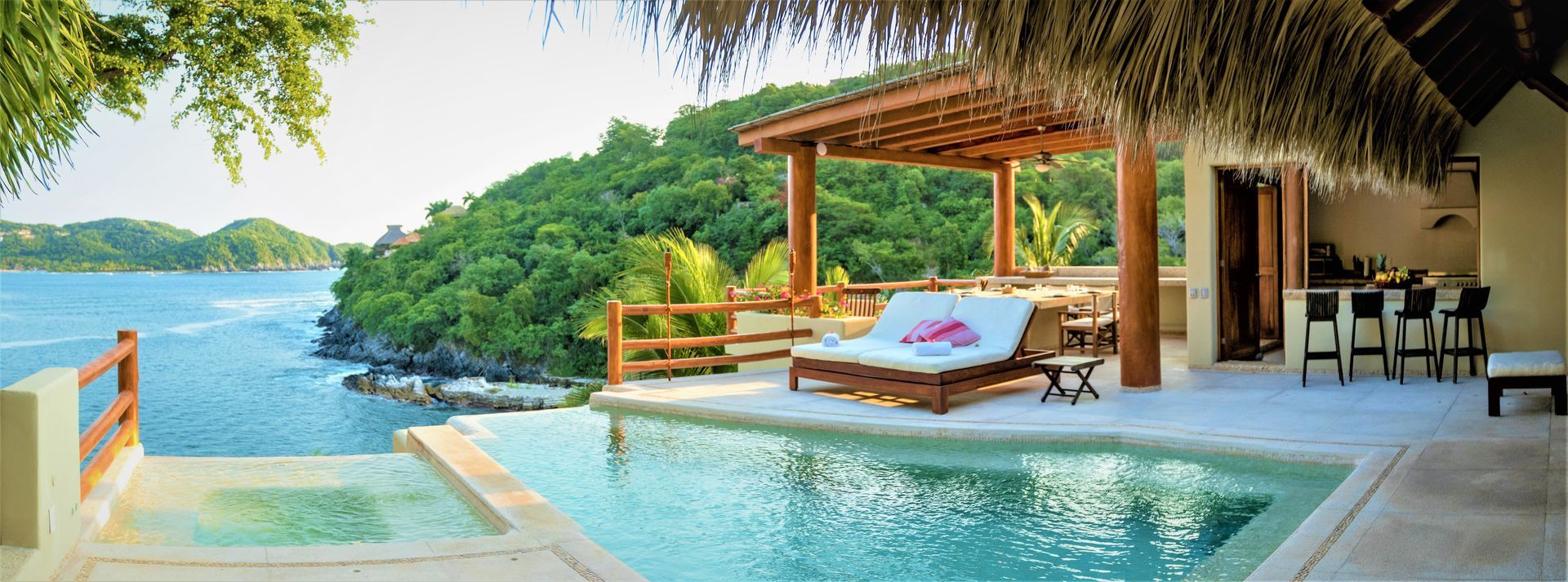 Piscina tropical con vista al mar, cabaña de madera, sillas para descansar y bar.