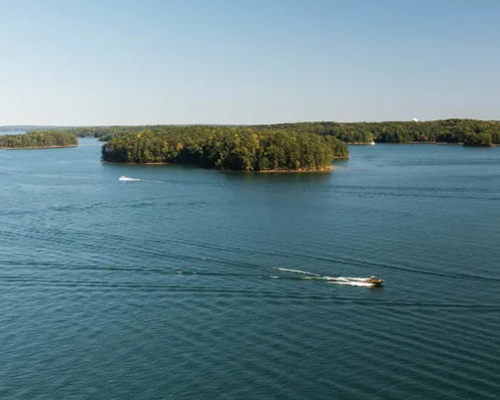 A boat is floating on top of a large body of water surrounded by small islands.