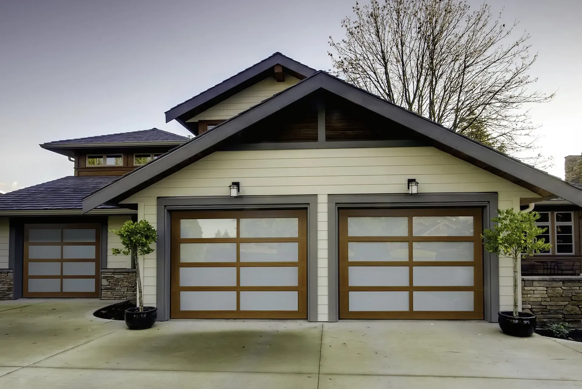 A house with two garage doors and a tree in front of it