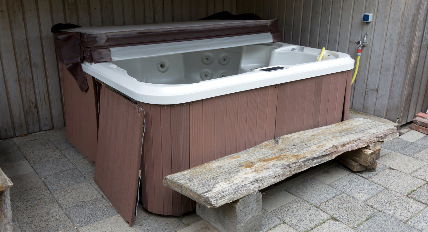 A hot tub is sitting on a patio next to a wooden bench.