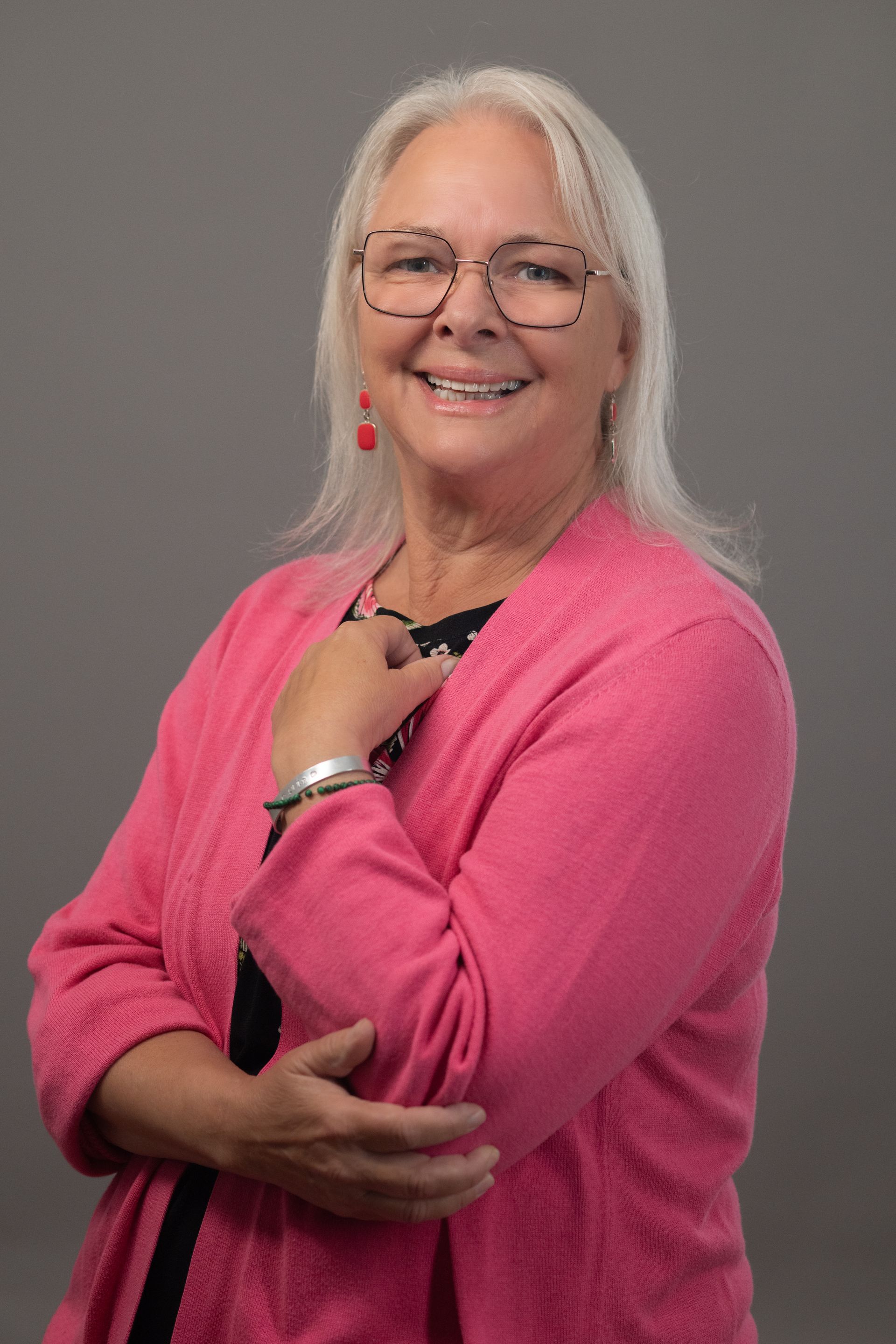 Woman in patterned jacket smiles, posing for photo.