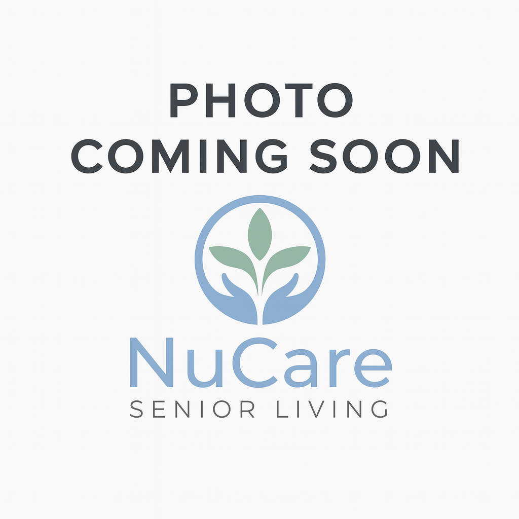 Woman wearing glasses, pink cardigan, smiling, looking at the camera. Against a gray background.