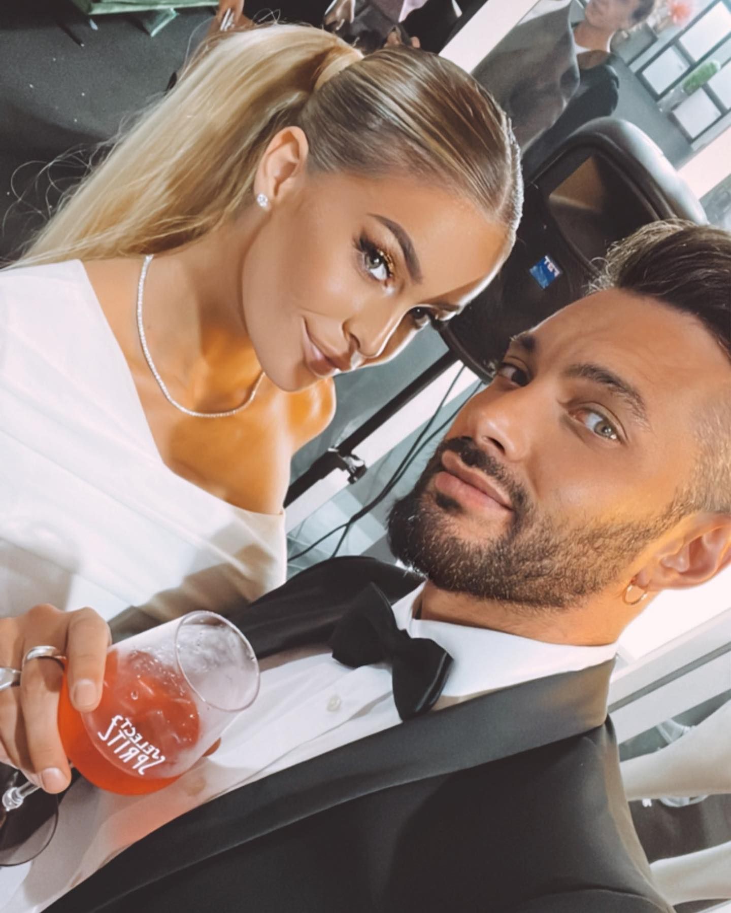 Un uomo in smoking e una donna in abito bianco posano per una foto.