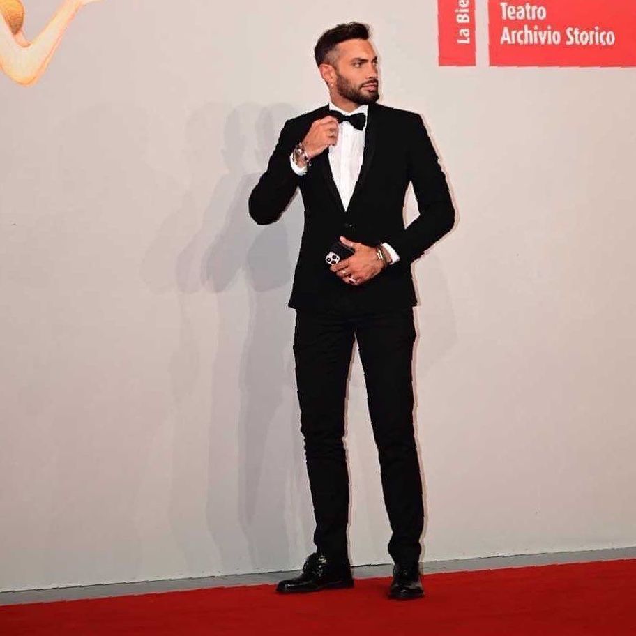 Un uomo in smoking è in piedi su un tappeto rosso