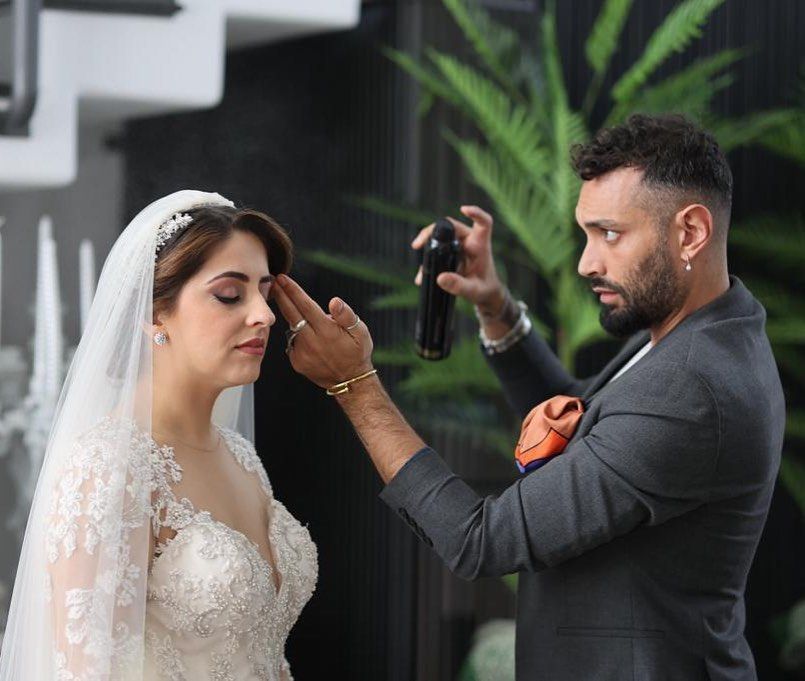 Un uomo sta truccando il viso di una sposa.