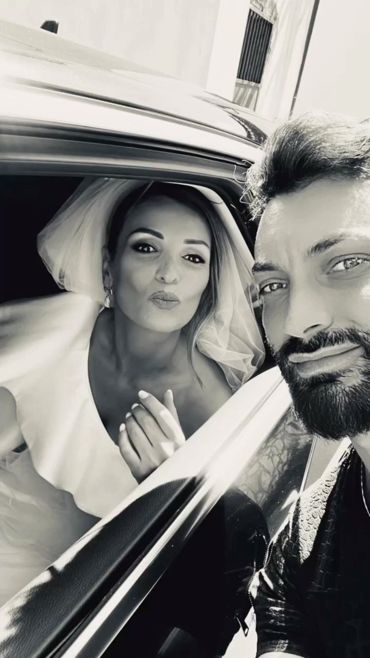 Una foto in bianco e nero di una sposa e uno sposo in macchina.