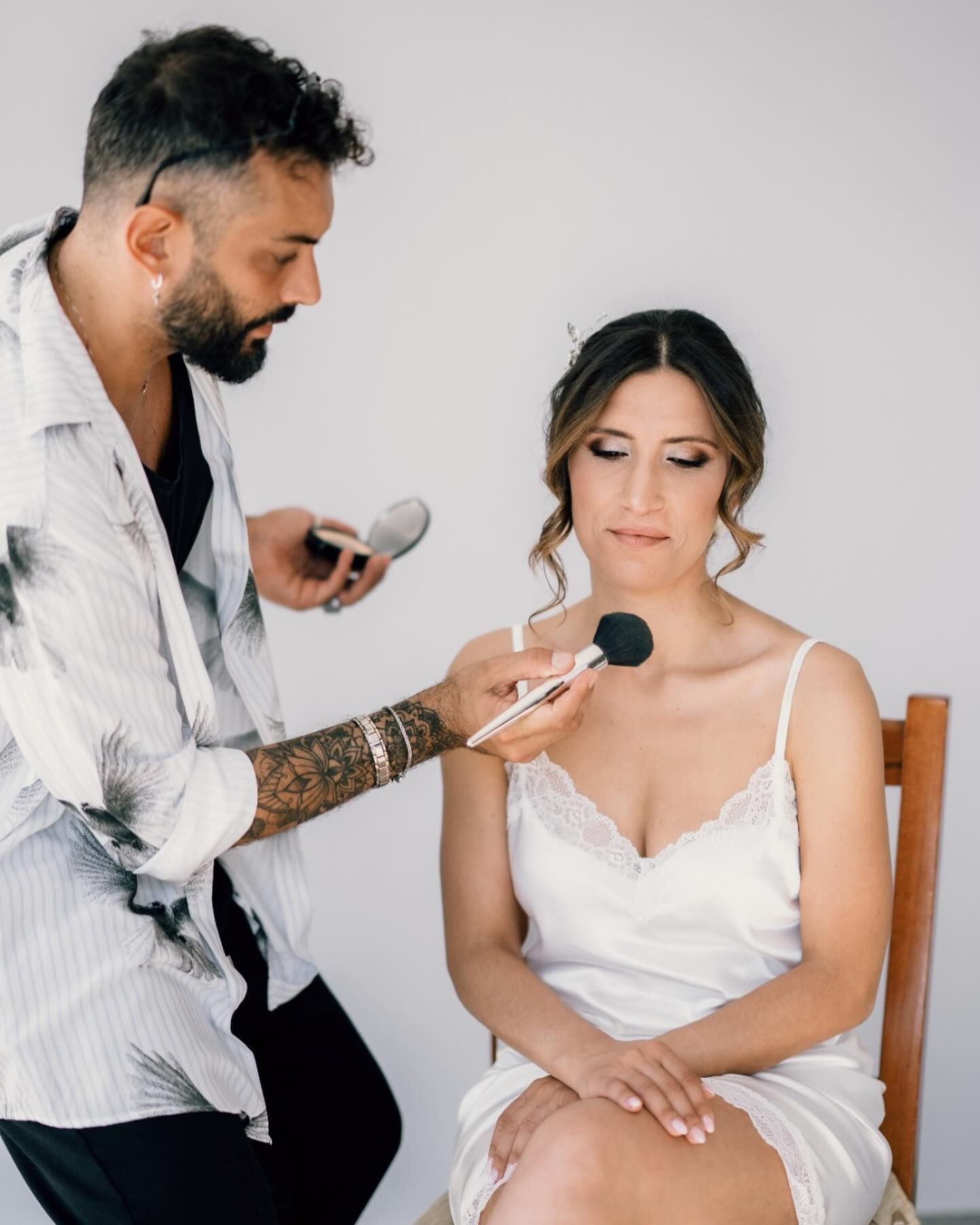 Un uomo sta truccando una donna seduta su una sedia.