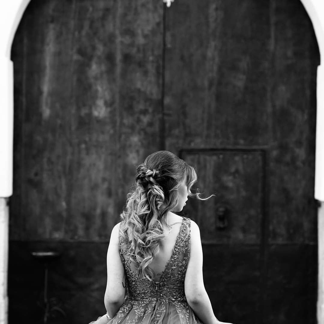 Una donna in abito è in piedi davanti a una porta in una foto in bianco e nero.