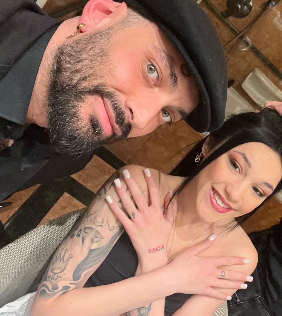 Un uomo e una donna stanno posando per una foto e la donna ha un tatuaggio sul braccio che dice 