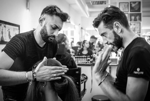 Due uomini stanno lavorando sui capelli di una donna in un salone.