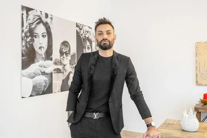 Un uomo in giacca e cravatta è in piedi davanti a un dipinto su una parete.