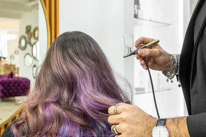 Una donna con i capelli viola si sta facendo tingere i capelli dal parrucchiere.