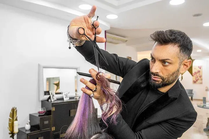 Un uomo sta tagliando i capelli di una donna con le forbici in un salone.