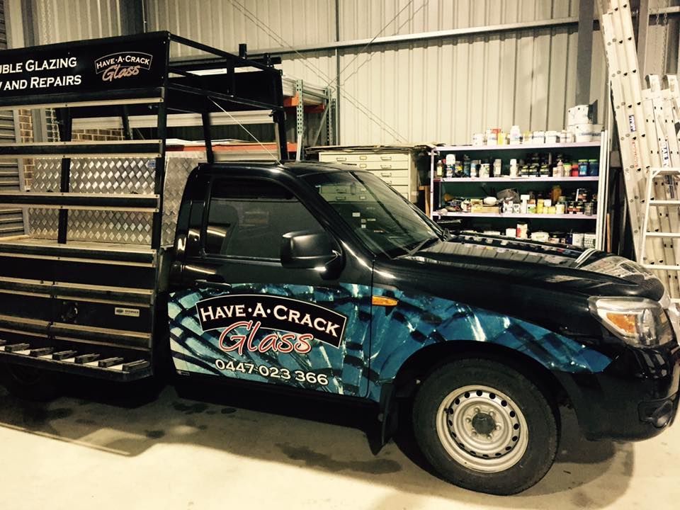 A black truck with a cage on top of it is parked in a garage.