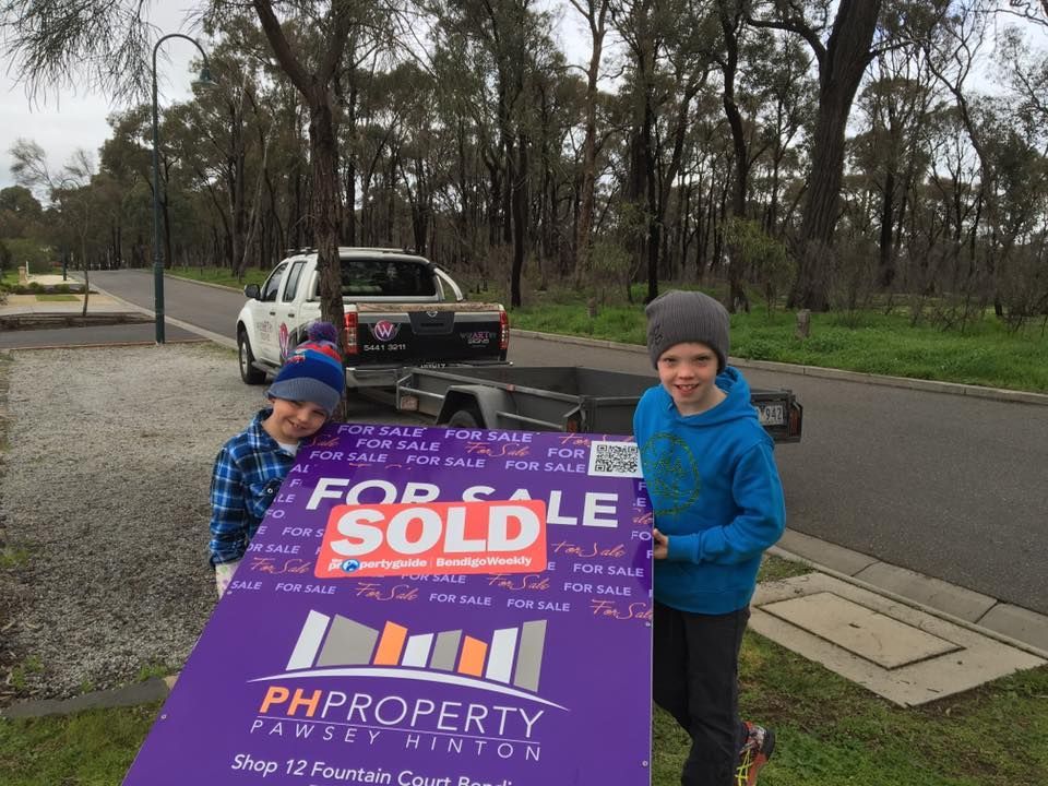 Two boys holding a purple sign that says for sale