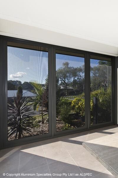 Large windows with dark frames overlooking a green yard and sunny sky.