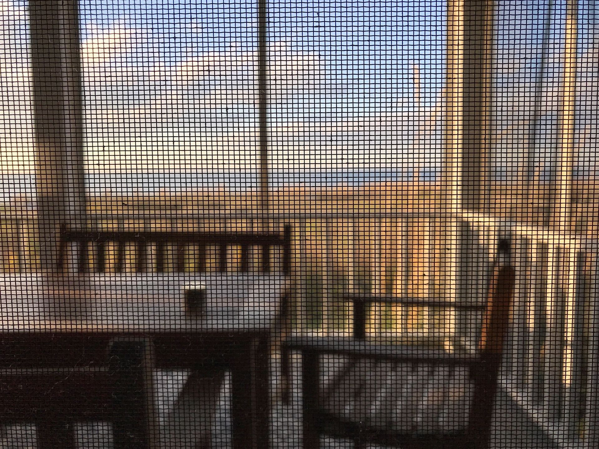 A blurry picture of a deck with a table and chairs behind a screen.