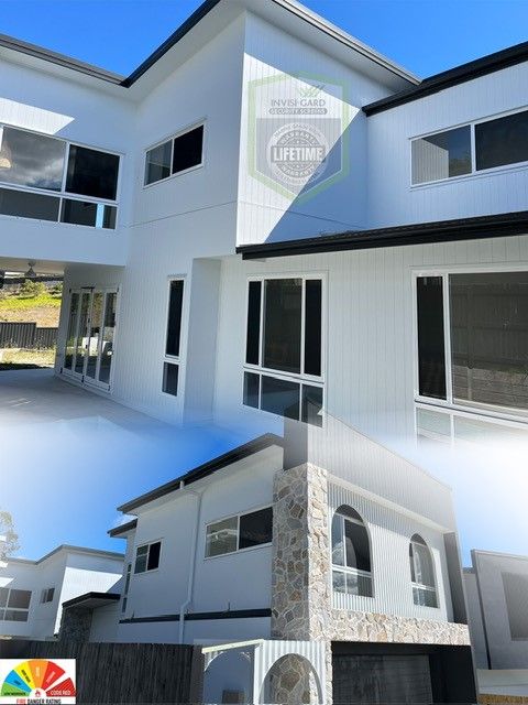 White modern house with large windows, stone accents, and black roof trim.