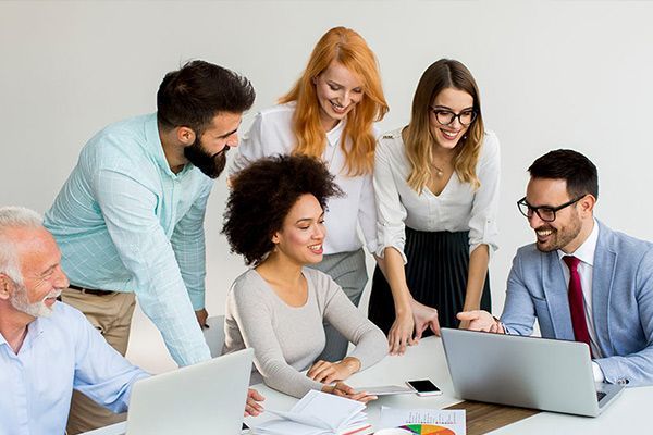 A group of people are sitting around a table looking at laptops.