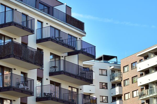 A row of apartment buildings with balconies and a blue sky in the background.