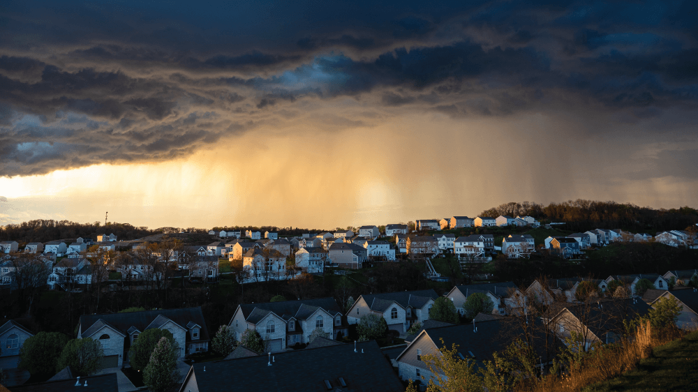 A storm is coming over a residential area at sunset.