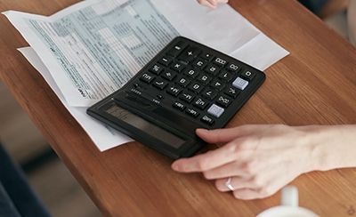 Una persona está usando una calculadora en una mesa de madera.