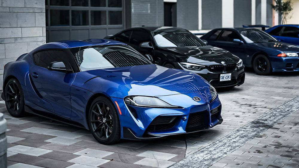 A row of blue and black sports cars parked in front of a garage.
