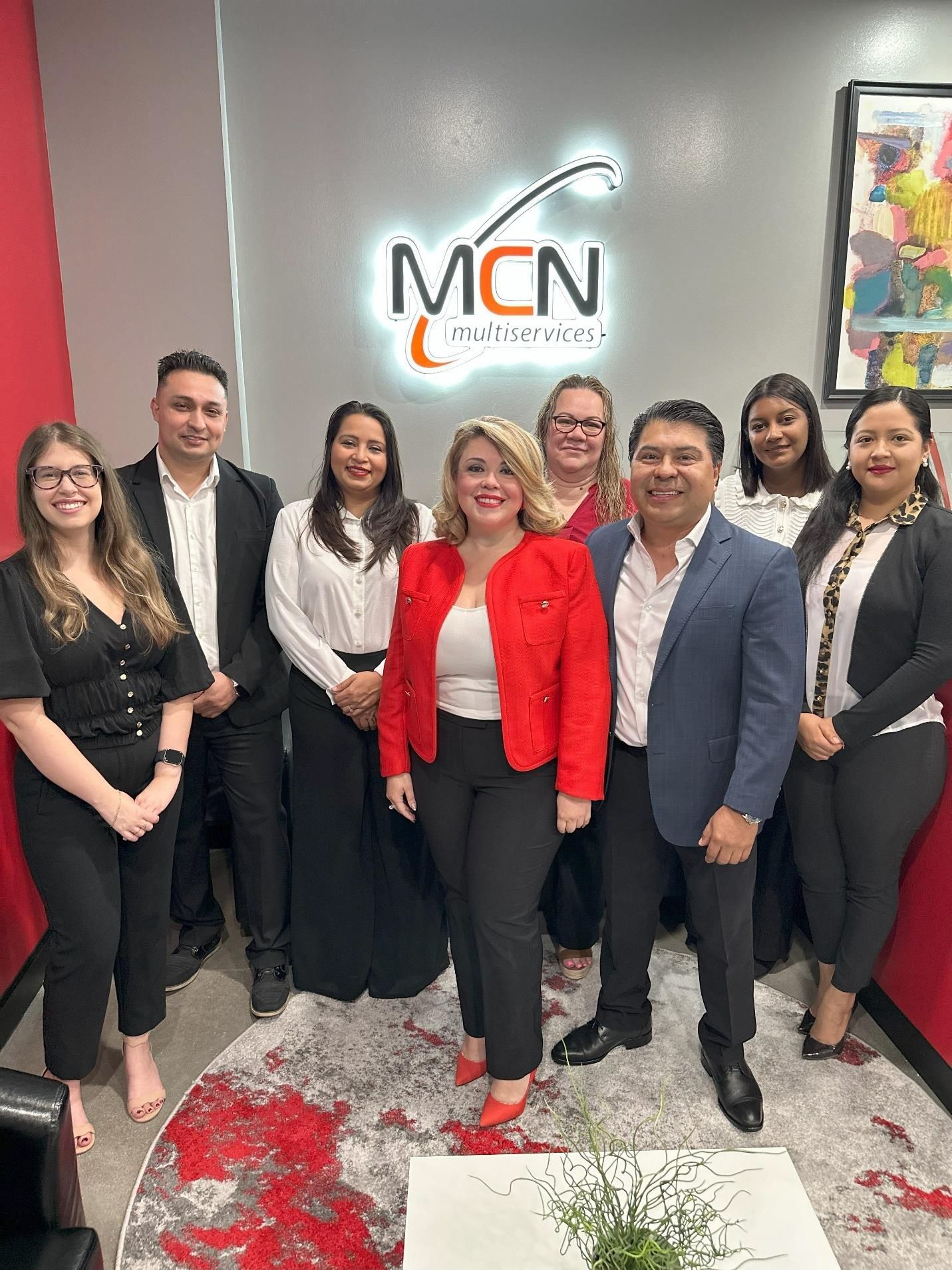 Un grupo de personas posa para una fotografía frente a un cartel de mcn.