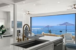 Bright kitchen overlooking ocean patio and blue sea through large open window