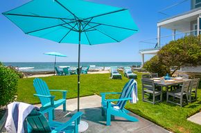 Oceanfront patio with turquoise chairs and umbrella overlooking the beach and sea