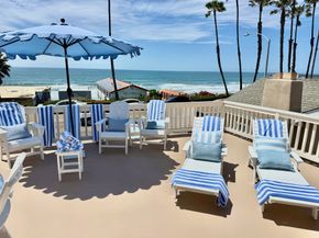 Beachside patio with blue-and-white loungers and umbrellas overlooking the ocean