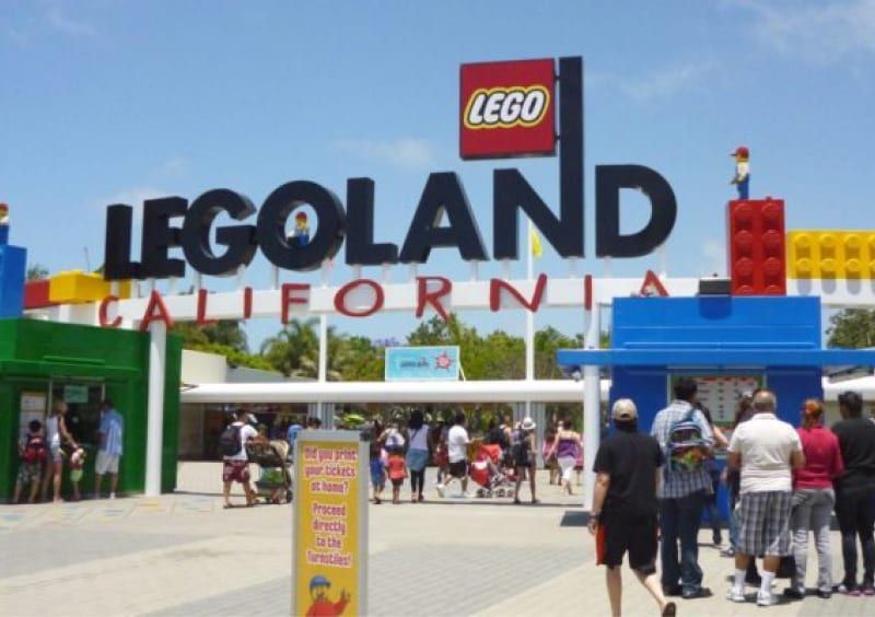 Entrance to Legoland California with sign, blue gate, and visitors walking inside