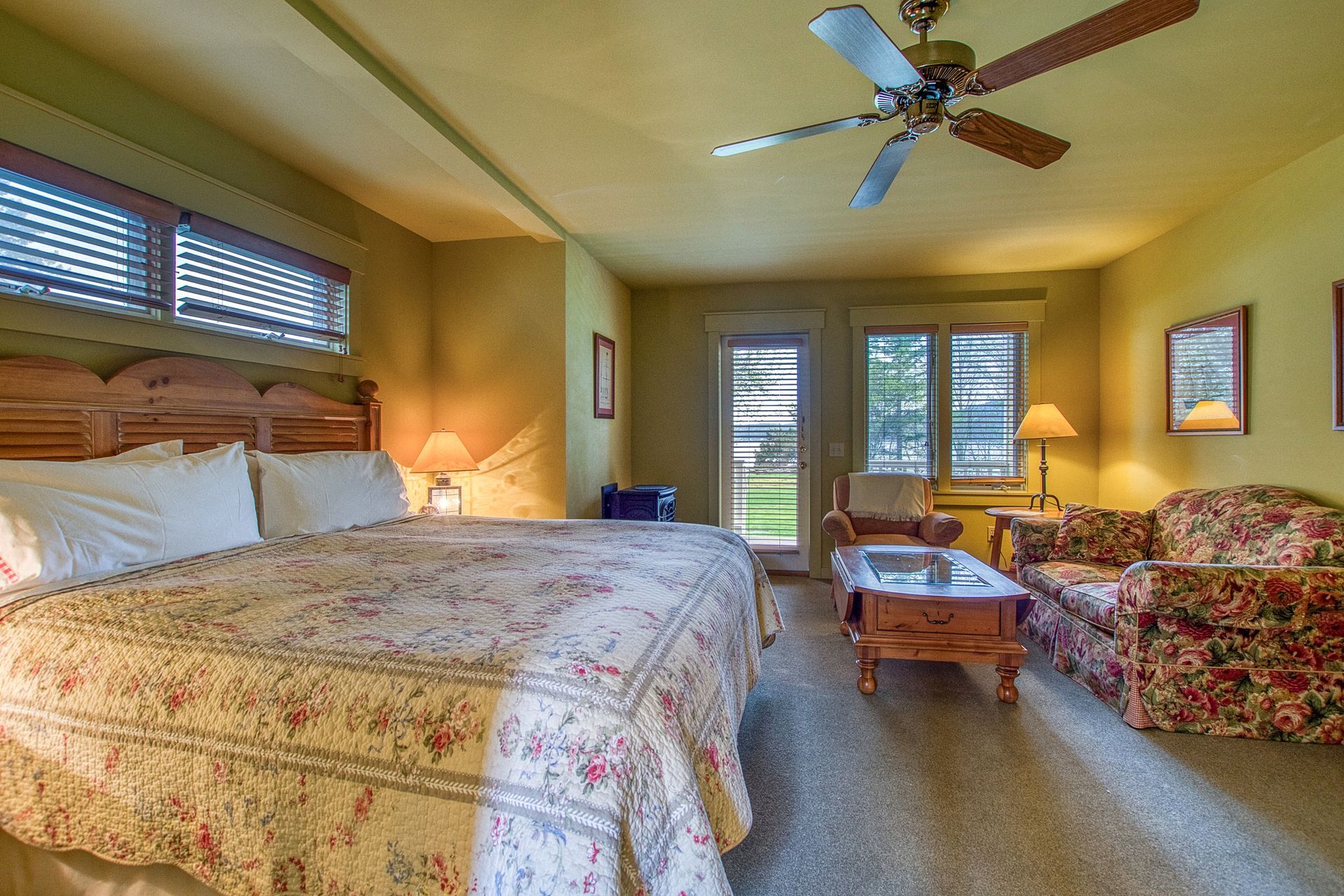 A bedroom with a king size bed a couch a coffee table and a fireplace