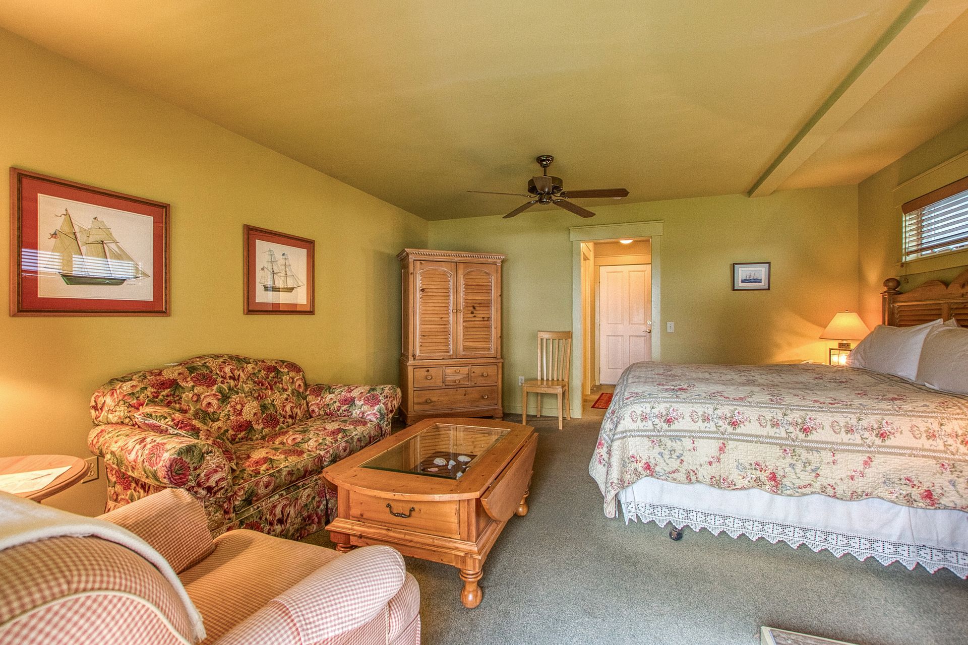 A bedroom with a bed , chair , coffee table and window.