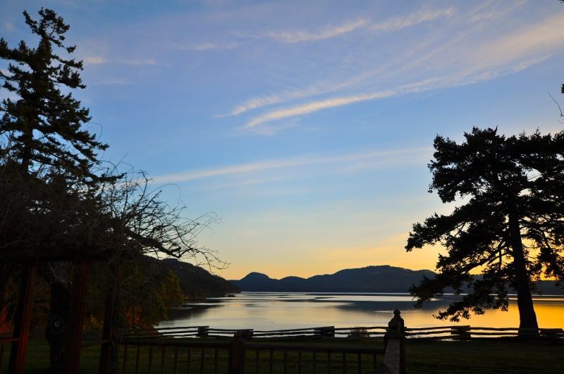 A sunset over a lake with trees in the foreground