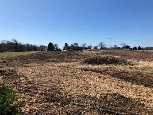 A dirt field with a house in the background