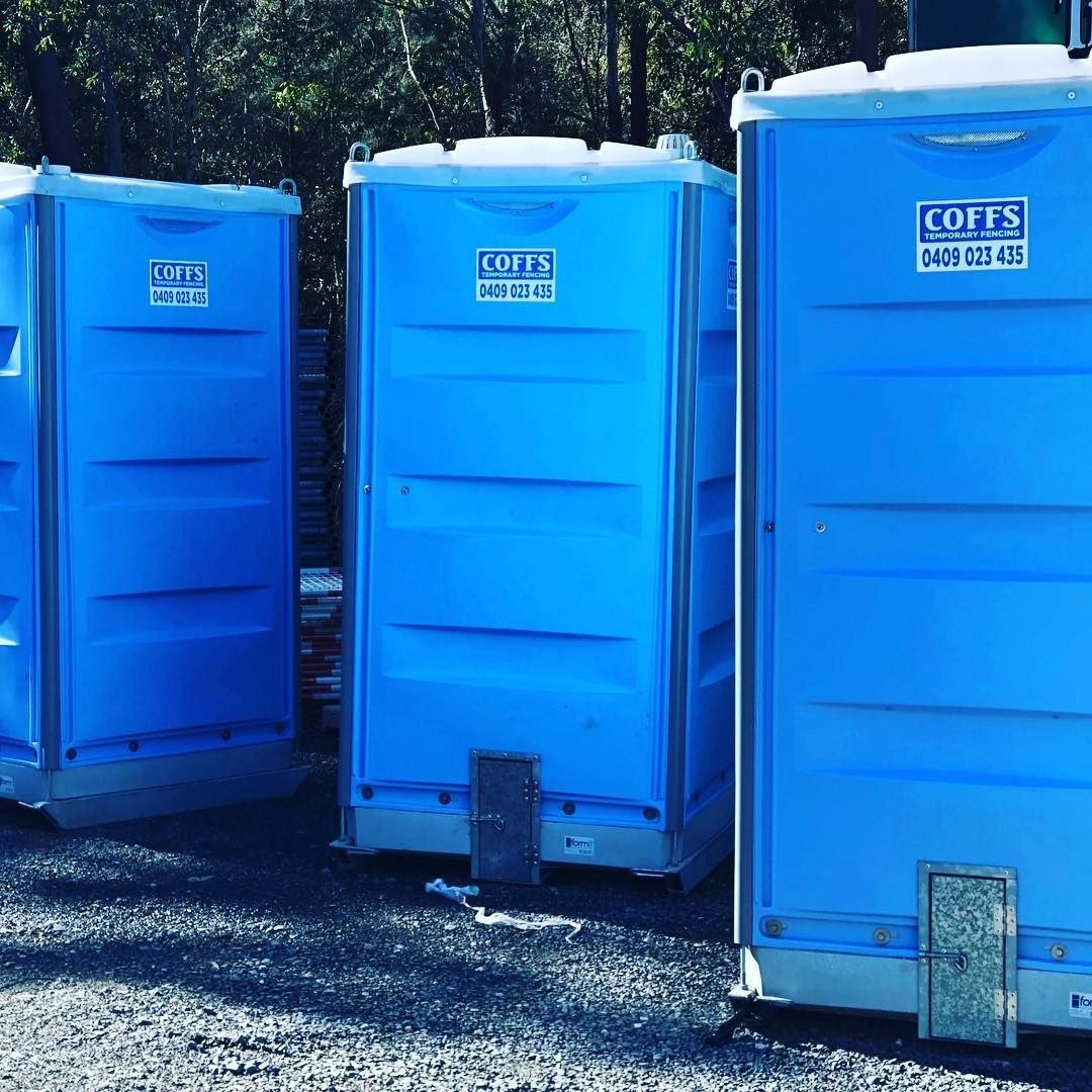 Three Blue Portable Toilets Are Parked Next To Each Other In A Gravel Lot — Coffs Temporary Fencing Pty Ltd In Grafton, NSW