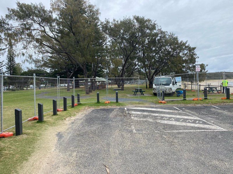 A White Van Is Parked In A Parking Lot Behind A Fence — Coffs Temporary Fencing Pty Ltd In Nambucca Heads, NSW
