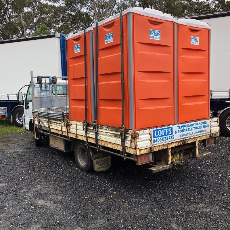 A Coffs Truck Is Parked In A Gravel Lot With Portable Toilets — Coffs Temporary Fencing Pty Ltd In Urunga, NSW