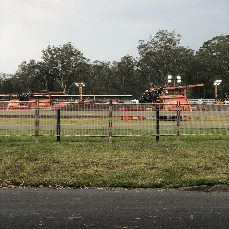 A Fence Surrounds A Field With A Lot Of Vehicles In It — Coffs Temporary Fencing Pty Ltd In Moonee Beach, NSW