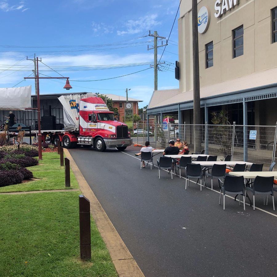A Red And White Semi Truck Is Parked In Front Of A Building — Coffs Temporary Fencing Pty Ltd In Nambucca Heads, NSW