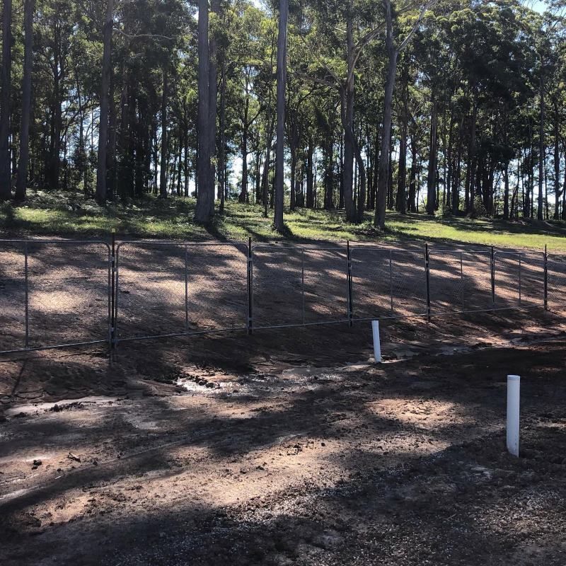 A Fenced In Area With Trees In The Background — Coffs Temporary Fencing Pty Ltd In Urunga, NSW