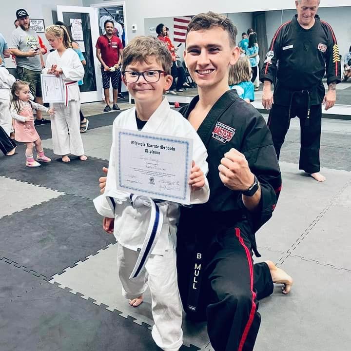 A man kneeling next to a young boy holding a certificate