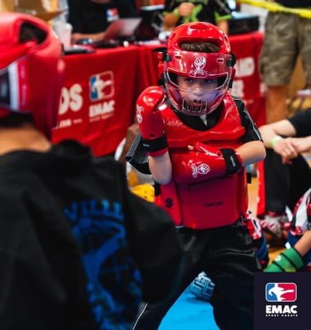 A young boy wearing a red helmet and boxing gloves