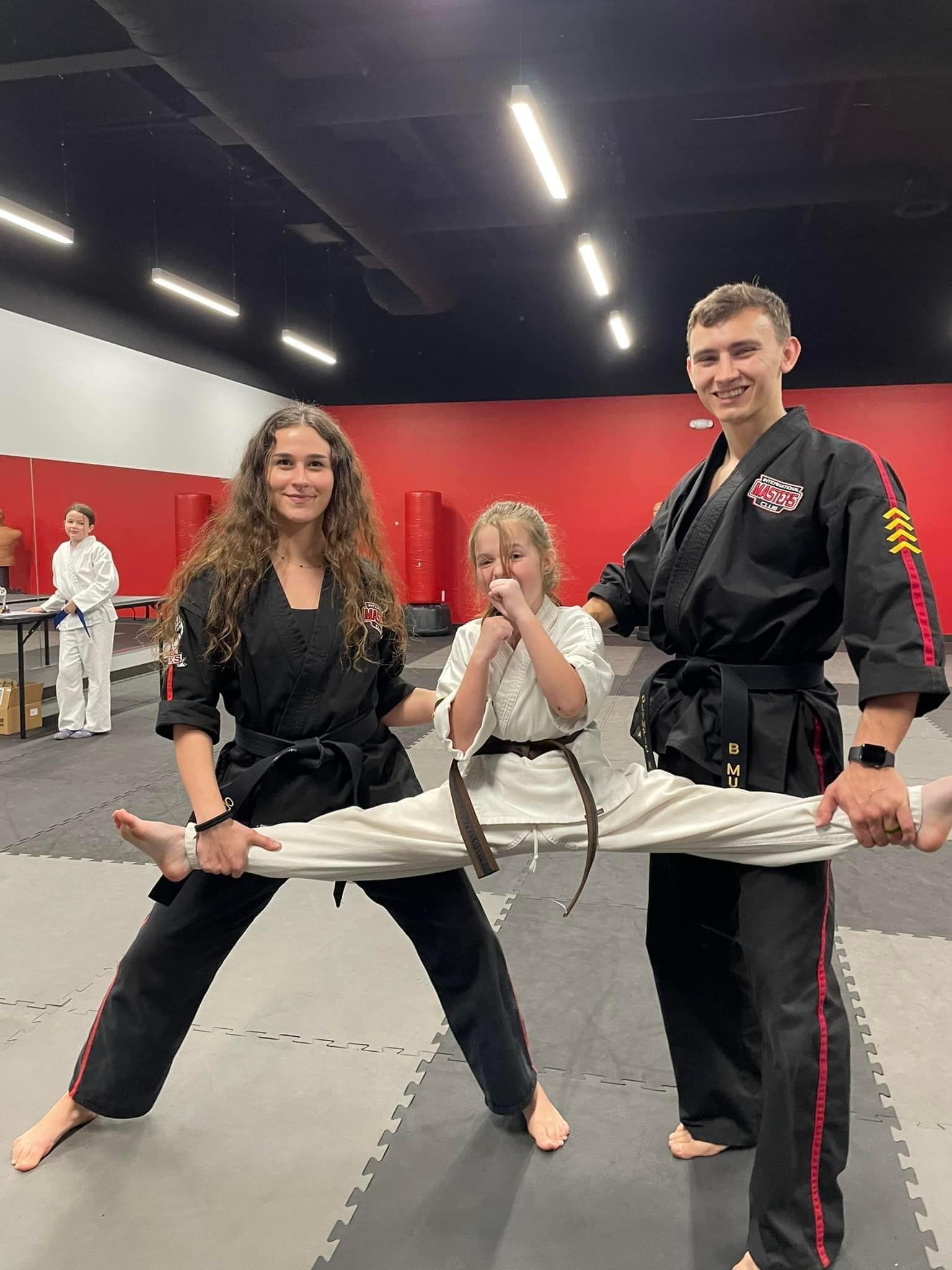 A man is holding a child 's leg in a karate class.
