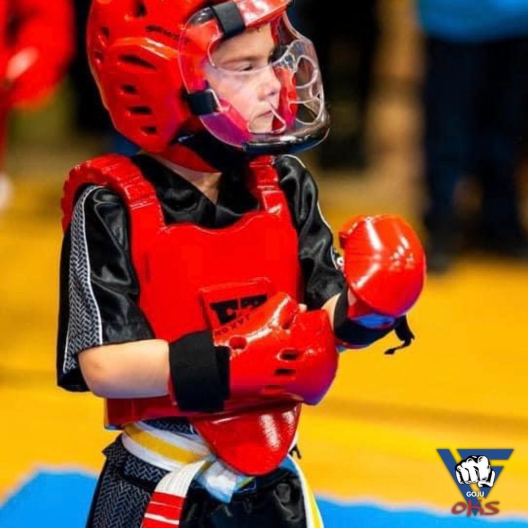 A young boy wearing red boxing gloves and a helmet