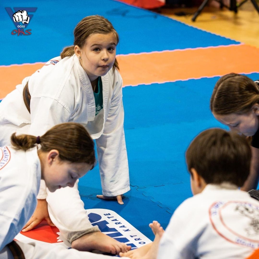 A group of kids are playing on a mat that says karate