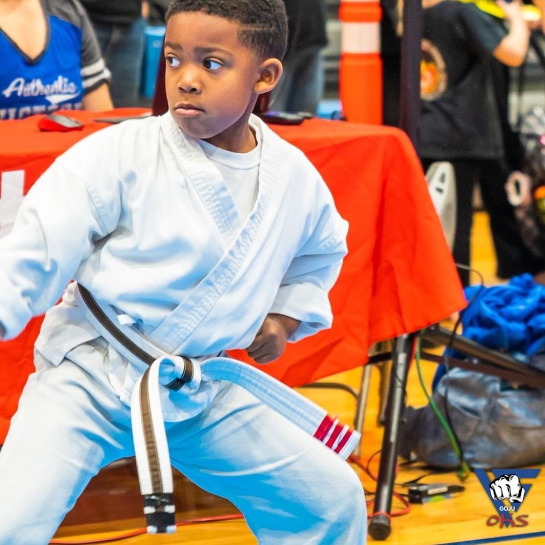 A young boy in a white karate uniform with a blue belt